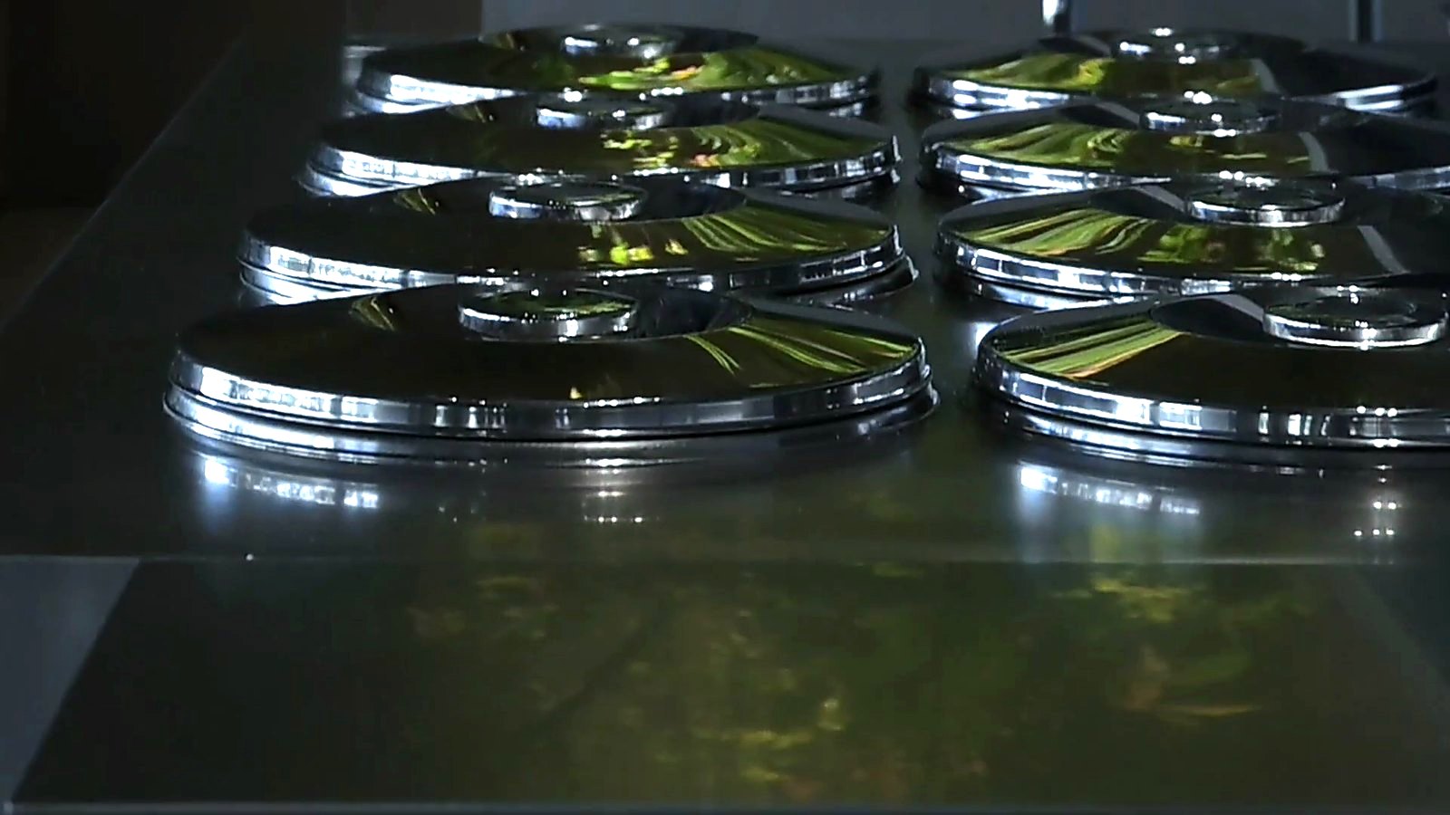 A row of pozzetto lids reflecting the greenery.