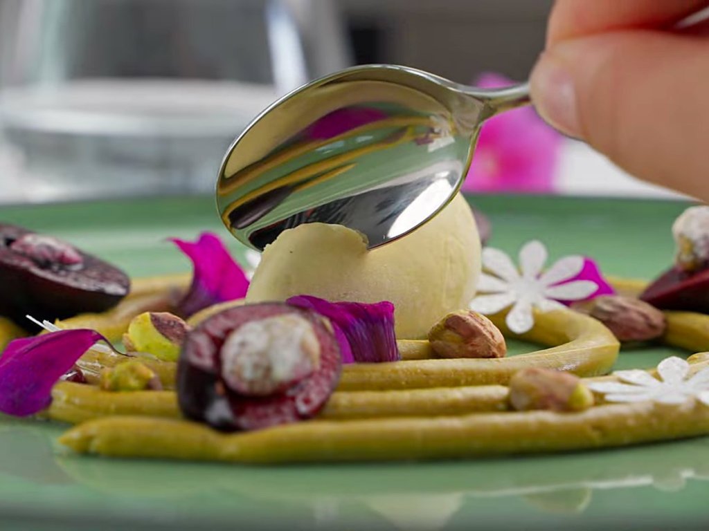 Gelato quenelle with figs and pistachio on a green plate