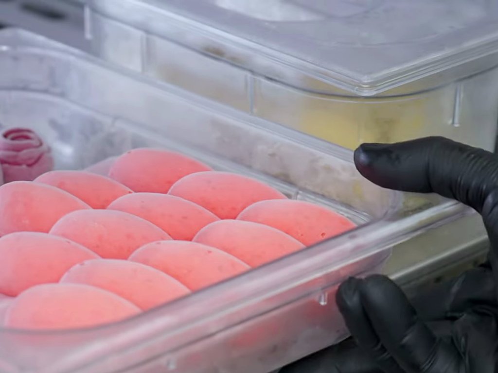 Tub of unmoulded strawberry gelato quenelles
