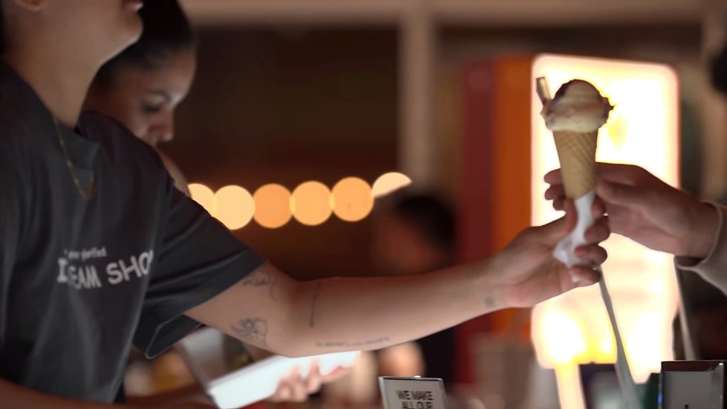 Gelato cone handed across the counter at night