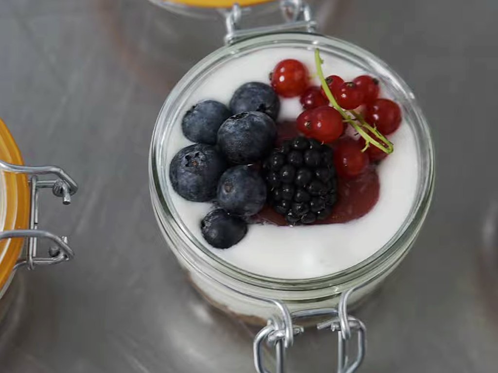 A layered jar dessert with fresh berries.