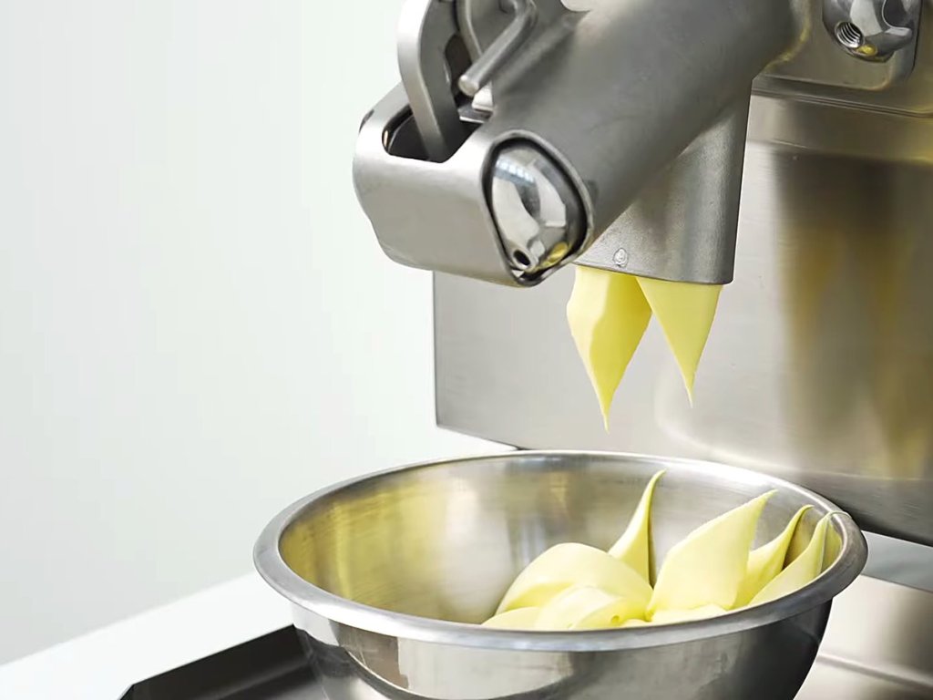 Pastry cream ribbons folding into a steel bowl