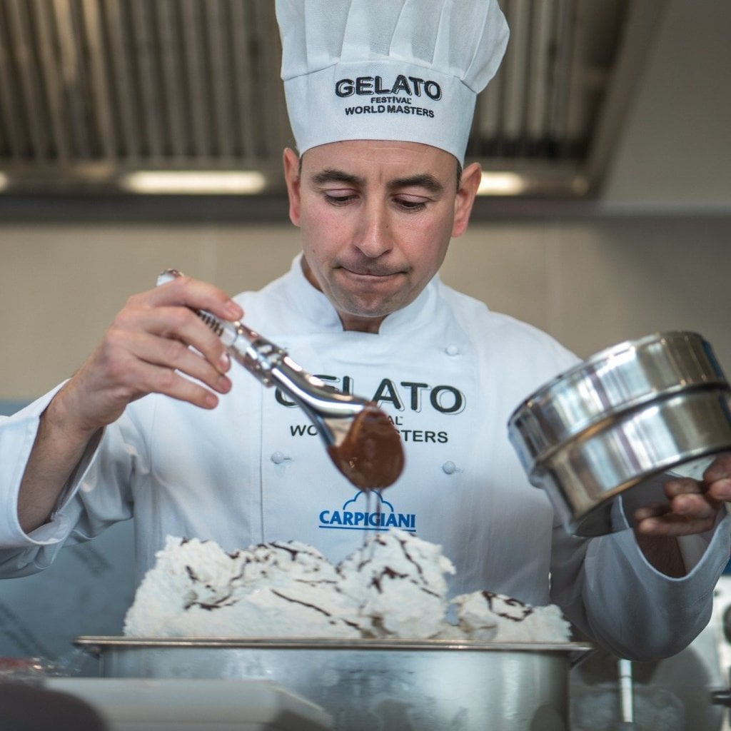 Gelato maker decorating a tub of gelato in a laboratory