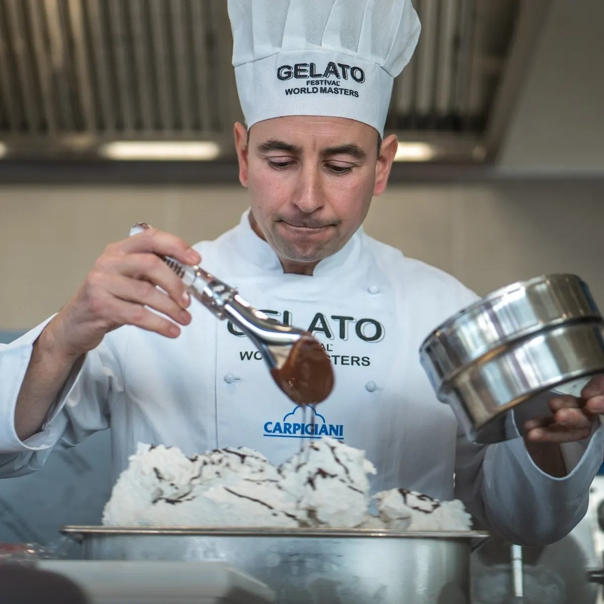 Gelato maker decorating a tub of gelato in a laboratory